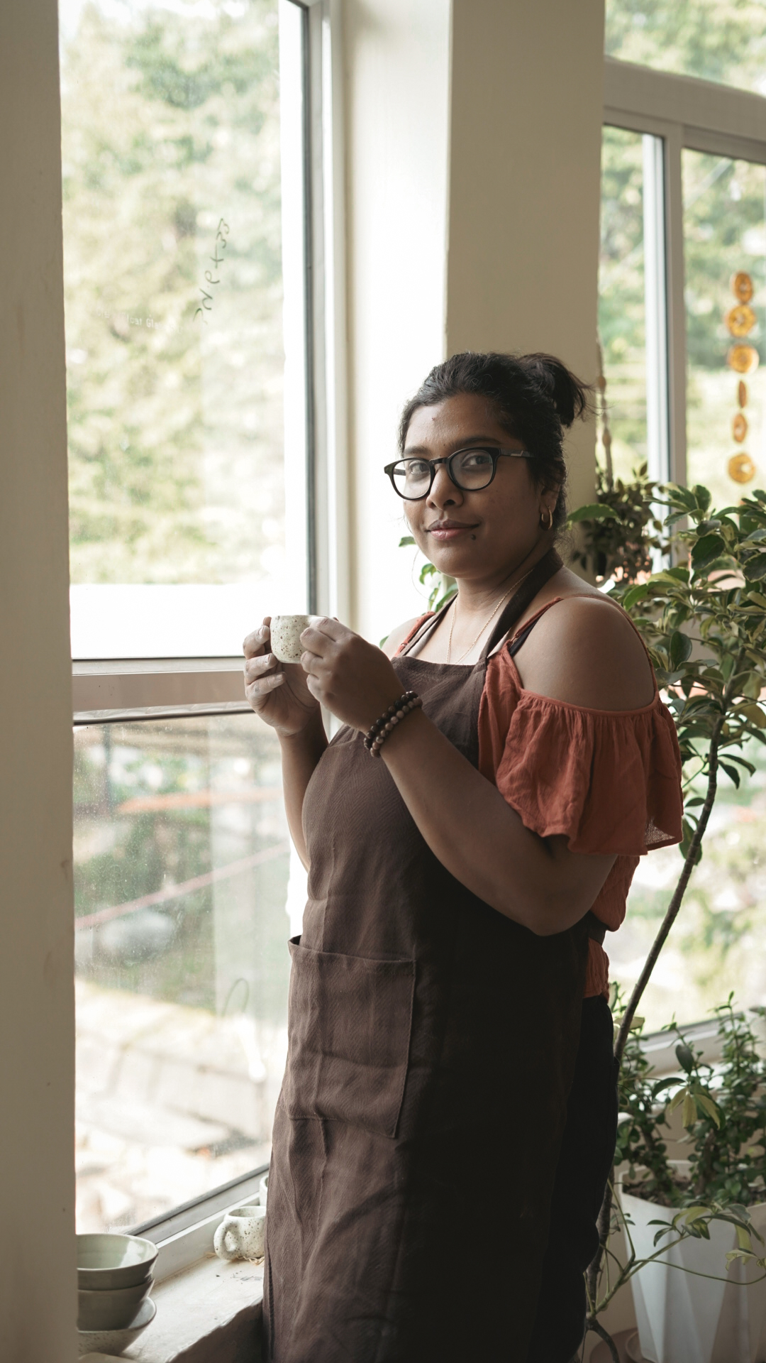 Founder holding a handmade cup in the sunlit studio